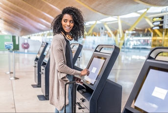 woman using check in machine at airport to avoid checked bag fees