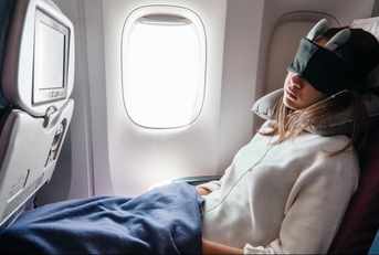 Woman sleeping on airplane with eye mask on