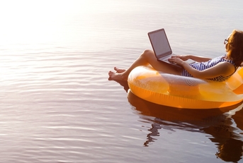 woman floating in lake with laptop