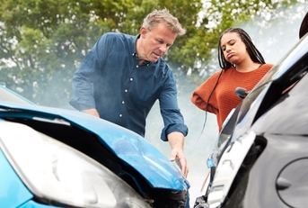 Two people looking at cars after accident