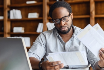 Man looking at papers and computer