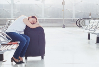 Woman sleeping on luggage at airport