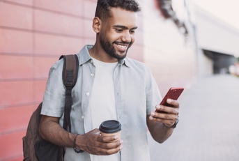 Man holding coffee and looking at phone