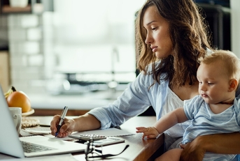 Working mother taking notes while calculating budget