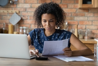 Woman looking at paperwork and using calculator