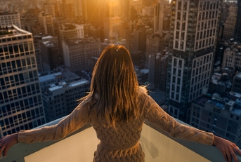 Rich woman enjoying the sunset standing on the balcony of a luxury apartments in New York City