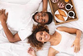 Couple enjoying hotel breakfast in bed