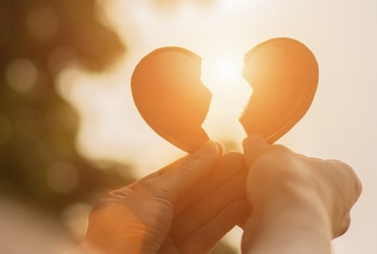 hands holding broken heart pieces in the sun 