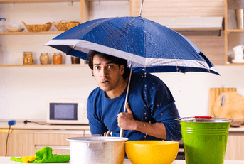 Man with a roof leak standing under umbrella