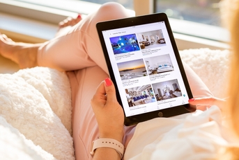 Woman holding iPad with Airbnb listings