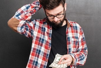 confused man standing over chalkboard while holding money