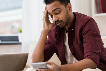 confused man with calculator at home