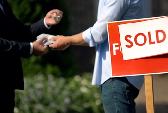 People shaking hands by 'sold' house sign