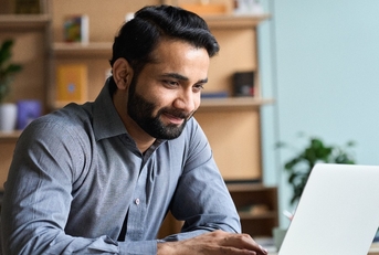 Smiling indian business man working on laptop 