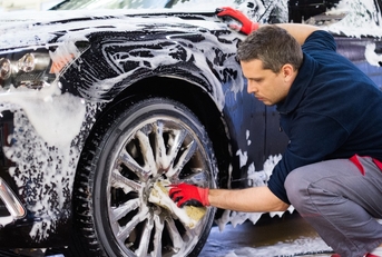 Man worker washing car's alloy wheels on a car wash