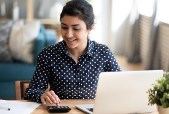 woman using a calculator and a laptop