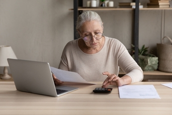 a woman using a calculator while holding a paycheck page