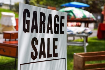 Garage sale sign on the lawn of a suburban home