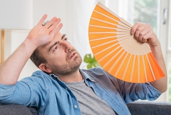 One man sweating suffering summer heatwave at home