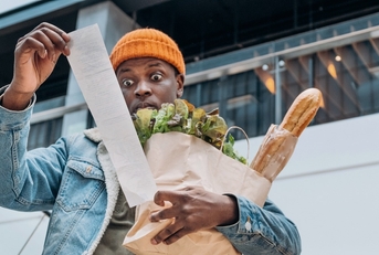 man in denim jacket looks at sales paper receipt