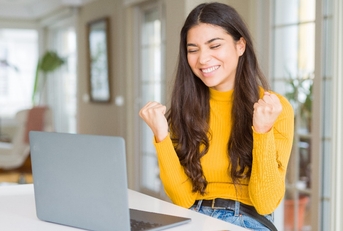 Young woman using computer laptop very happy and excited doing winner gesture