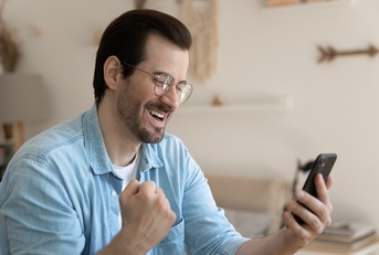 Overjoyed man wearing glasses holding smartphone