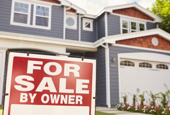 large suburban house with ‘for sale’ sign displayed outside