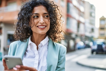 Woman on city street using her cell phone