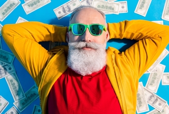adult man with white beard lying on top of money
