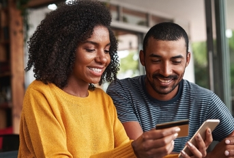 man looking at his girlfriend shopping online in cafe