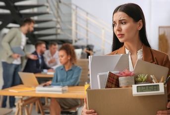 dismissed young woman carrying box with stuff in office