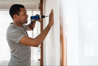 male using electric drill on the wall 