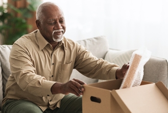 retired senior man packing stuff in box indoors