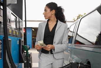 businesswoman counting money while looking on the meter of petrol pump