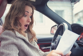 shocked woman in car reading insurance paper
