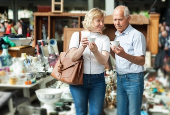 mature family couple choosing vintage dishes on street market