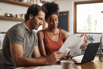  couple using their laptop and going through paperwork