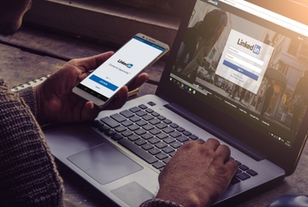 man using linkedin on smartphone and laptop