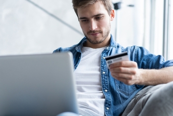 Man holding credit card and looking at laptop