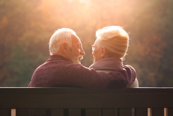senior couple sitting on bench in autumn park