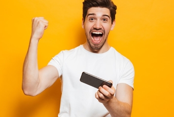 a happy adult man playing a mobile game