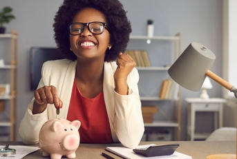 african american woman putting coins in piggy bank