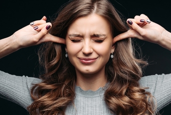 young beautiful woman closing eyes and blocking ears with fingers