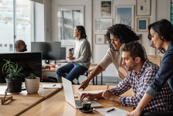 three young designers using a laptop together at work
