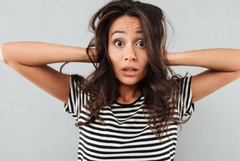 young woman holding her head stressfully in black and white striped shirt