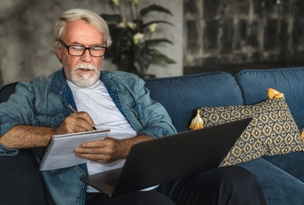 elderly man writing notes in notebook