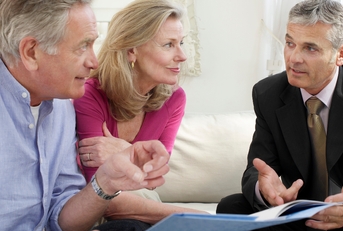 mature couple sitting on sofa with financial advisor
