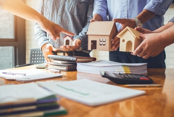 Several people in a meeting room holding model houses