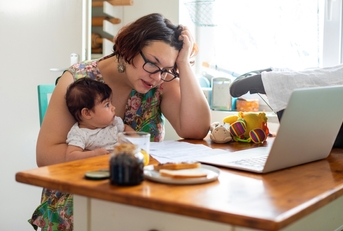 Woman holding baby and looking at computer