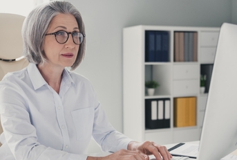 stylish senior lady with bob cut sitting on chair working at office on desktop